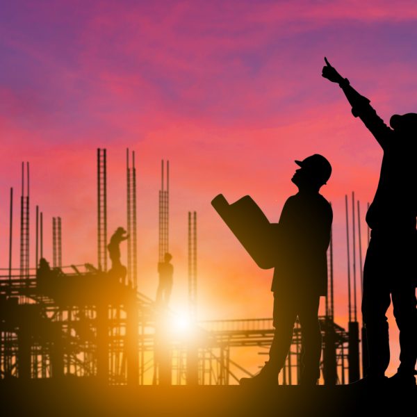 Silhouette of Engineer and worker with clipping path on building site, construction site at sunset in evening time.